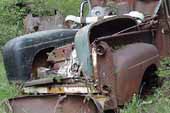 Original truck fenders and hoods stored in Ford pickup truck in vintage car junkyard