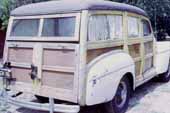 Bone-stock original Ford woodie wagon stored in vintage car wrecking yard for restoration